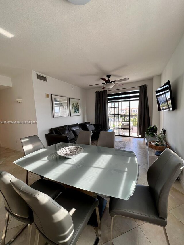 dining area featuring ceiling fan, light tile patterned floors, and a textured ceiling