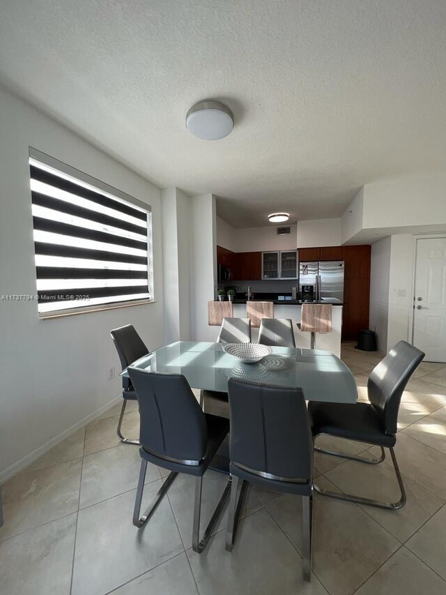 tiled dining space featuring a textured ceiling