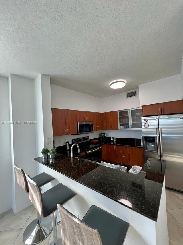 kitchen featuring light tile patterned flooring, stainless steel appliances, a kitchen breakfast bar, and kitchen peninsula