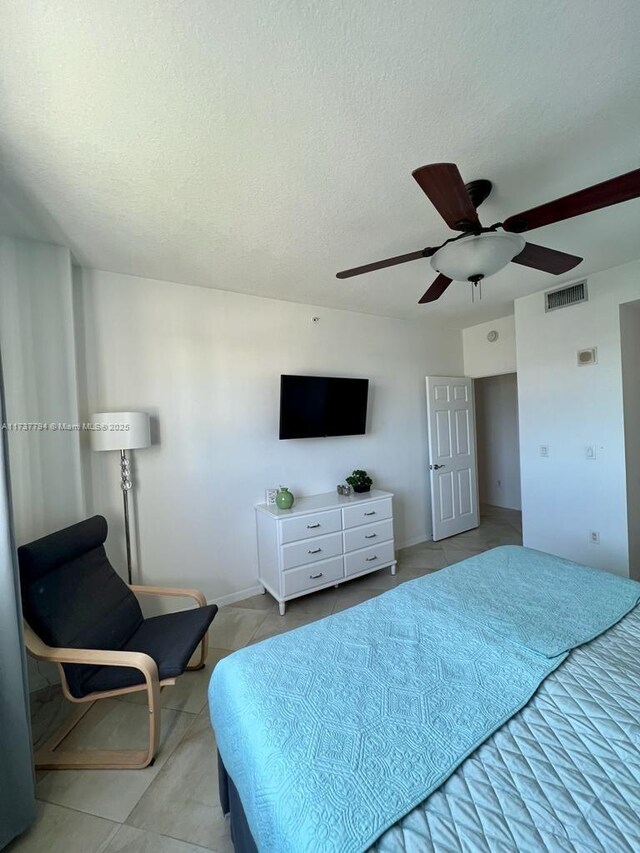 bedroom with light tile patterned flooring, ceiling fan, and a textured ceiling