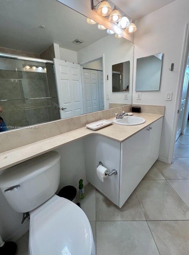 bathroom featuring tile patterned flooring, vanity, a shower with shower door, and toilet