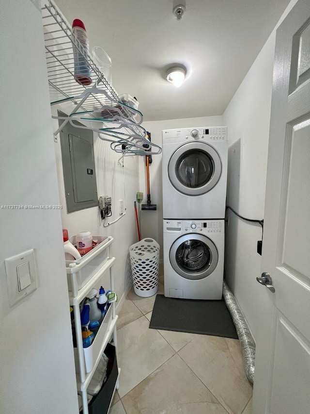 laundry room featuring light tile patterned flooring, stacked washer / drying machine, and electric panel