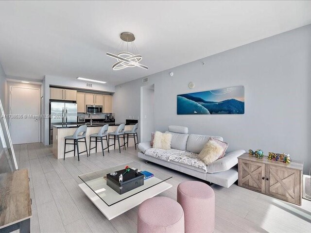 living room featuring sink, an inviting chandelier, and light hardwood / wood-style floors