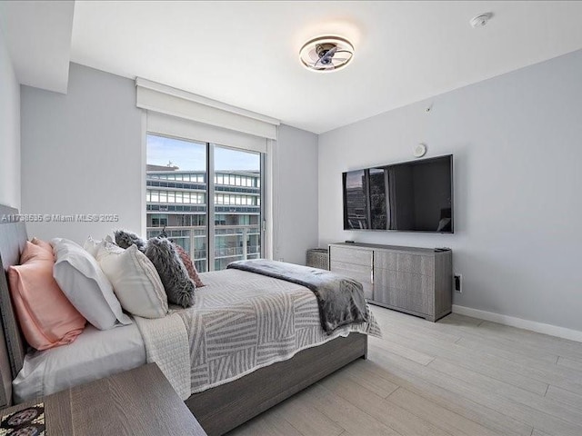 bedroom with access to outside, light wood finished floors, and baseboards