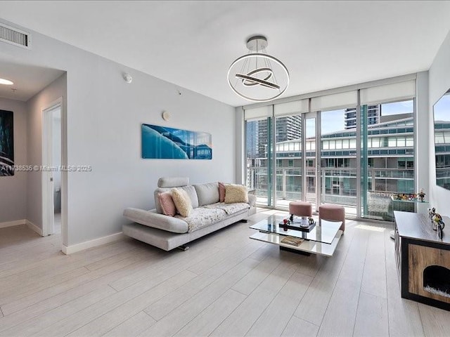 living room with expansive windows, wood finished floors, visible vents, and baseboards