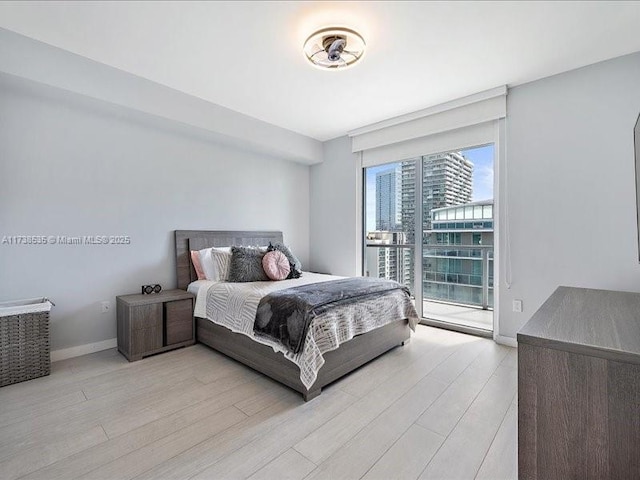 bedroom featuring light wood finished floors, access to exterior, and baseboards