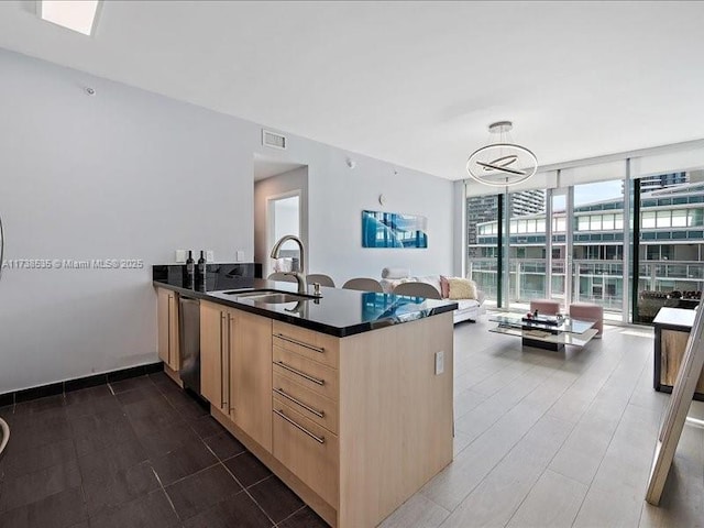 kitchen with a peninsula, a sink, stainless steel dishwasher, expansive windows, and light brown cabinetry