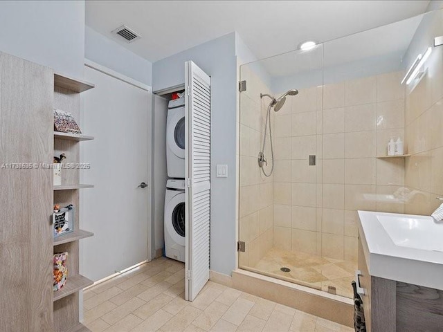 bathroom featuring stacked washer and dryer, a stall shower, and visible vents