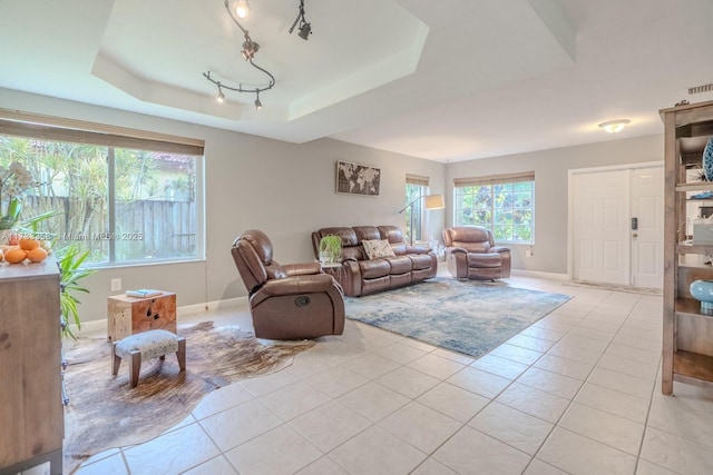 tiled living room featuring a raised ceiling and track lighting