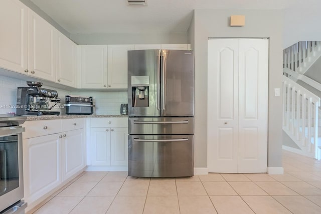 kitchen featuring light tile patterned flooring, tasteful backsplash, white cabinets, range, and stainless steel refrigerator with ice dispenser