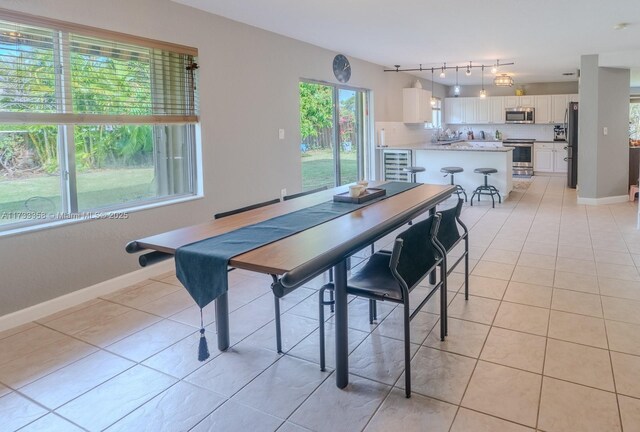 dining room with track lighting, beverage cooler, and light tile patterned floors