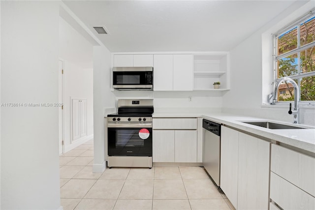 kitchen featuring stainless steel appliances, white cabinetry, sink, and light tile patterned floors