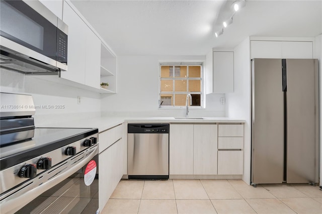 kitchen with white cabinetry, appliances with stainless steel finishes, sink, and light tile patterned floors