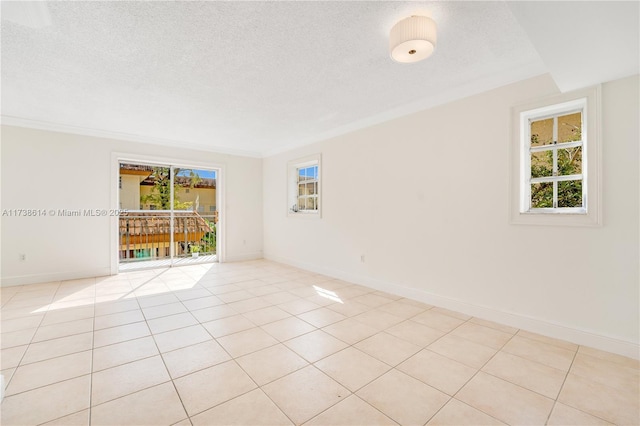 spare room with a healthy amount of sunlight, a textured ceiling, and light tile patterned floors