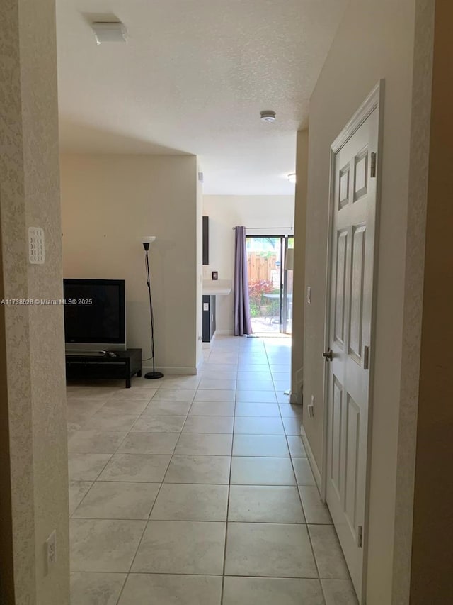 hallway with light tile patterned floors and a textured ceiling