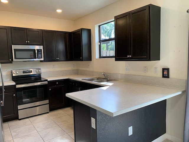 kitchen featuring appliances with stainless steel finishes, sink, light tile patterned floors, and kitchen peninsula