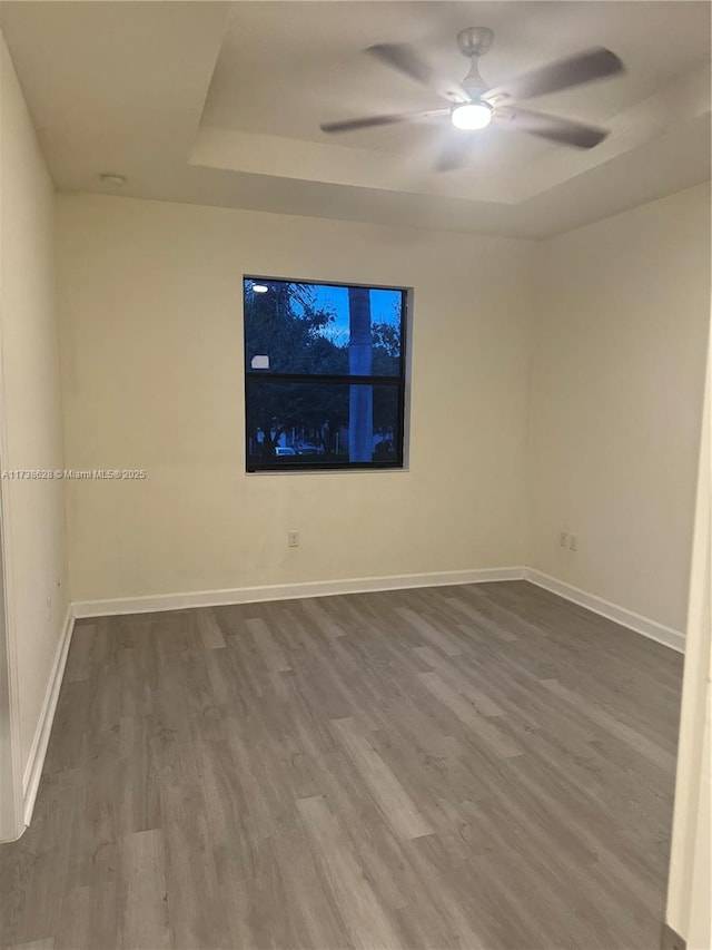 unfurnished room with hardwood / wood-style floors, a raised ceiling, and ceiling fan