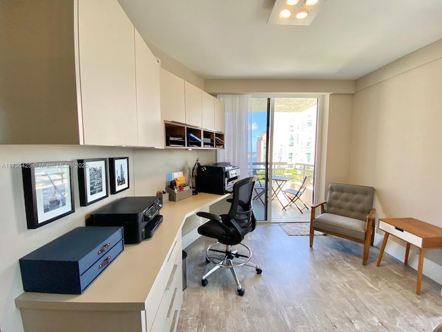 office space with built in desk and light hardwood / wood-style flooring