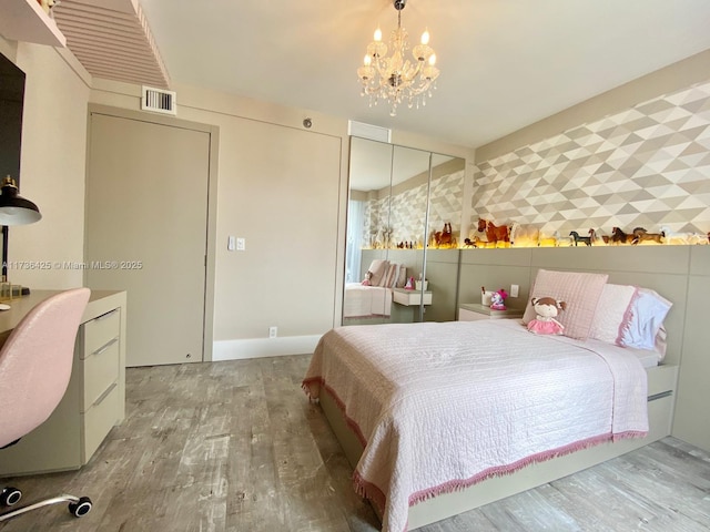 bedroom featuring wood-type flooring, a closet, and a notable chandelier