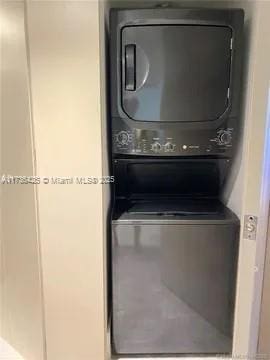 clothes washing area featuring stacked washer and clothes dryer