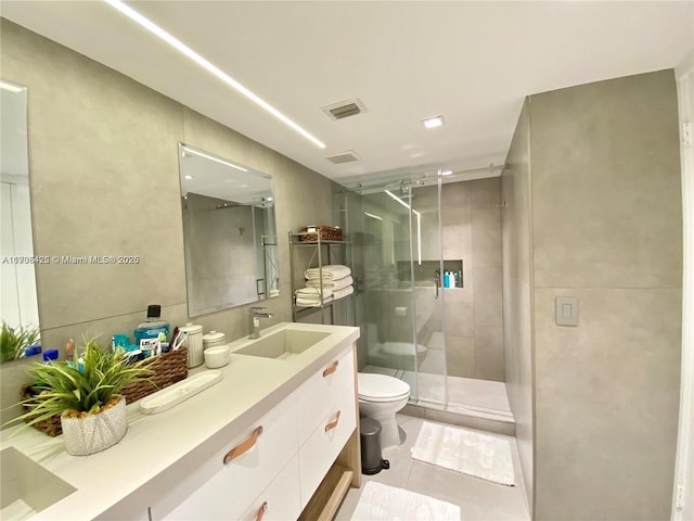 bathroom with vanity, toilet, a shower with shower door, and tile patterned flooring