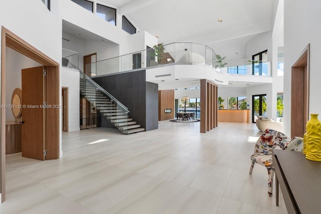 living room featuring beamed ceiling, a high ceiling, and stairway