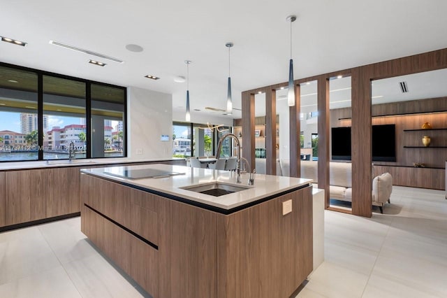 kitchen with a kitchen island with sink, hanging light fixtures, a sink, and modern cabinets