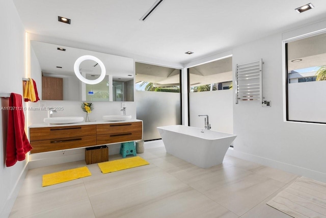 bathroom with a freestanding bath, plenty of natural light, a sink, and radiator