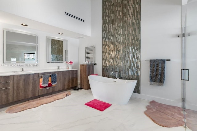 bathroom featuring double vanity, a freestanding tub, marble finish floor, and a sink