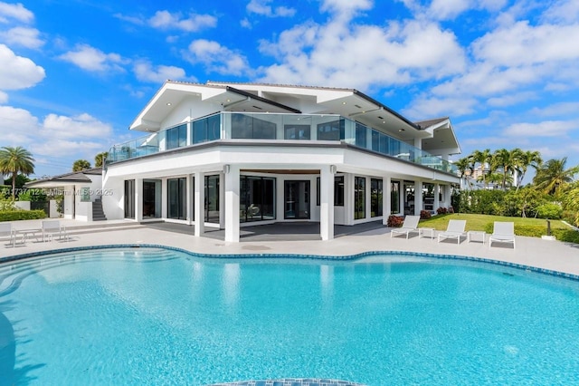 back of property with a patio area, an outdoor pool, and a balcony