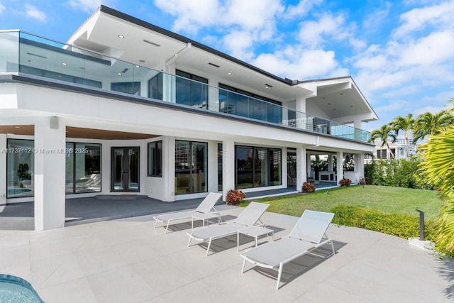 rear view of house with french doors, a lawn, a patio area, and stucco siding