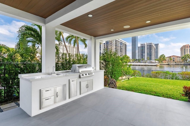 view of patio / terrace featuring a water view, a view of city, a sink, and area for grilling