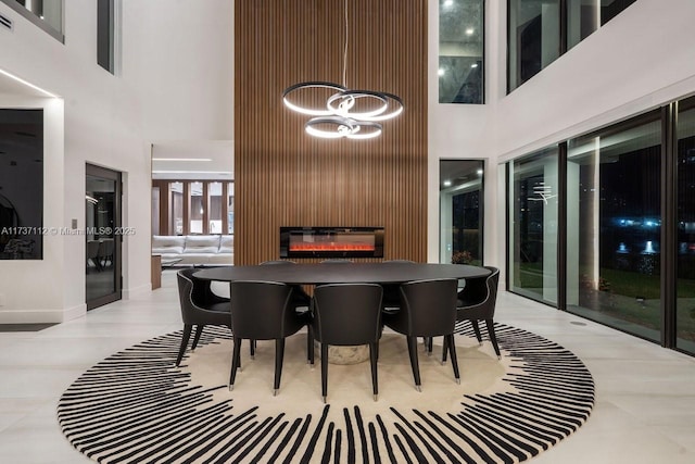 dining space with a high ceiling, baseboards, and a glass covered fireplace