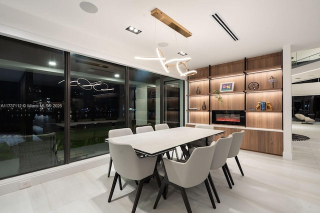 dining room with a glass covered fireplace, visible vents, and an inviting chandelier