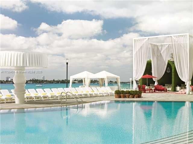 view of swimming pool featuring a gazebo, a water view, and a patio