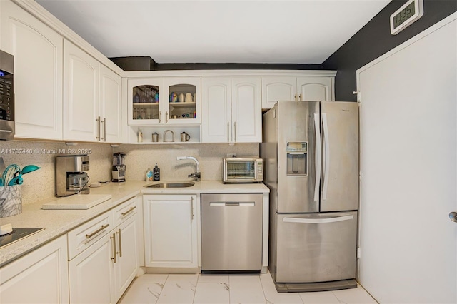 kitchen with tasteful backsplash, appliances with stainless steel finishes, sink, and white cabinets