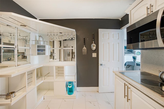 kitchen with white cabinetry, lofted ceiling, and black electric stovetop