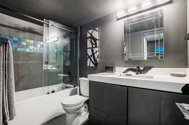 full bathroom with bath / shower combo with glass door, vanity, and toilet