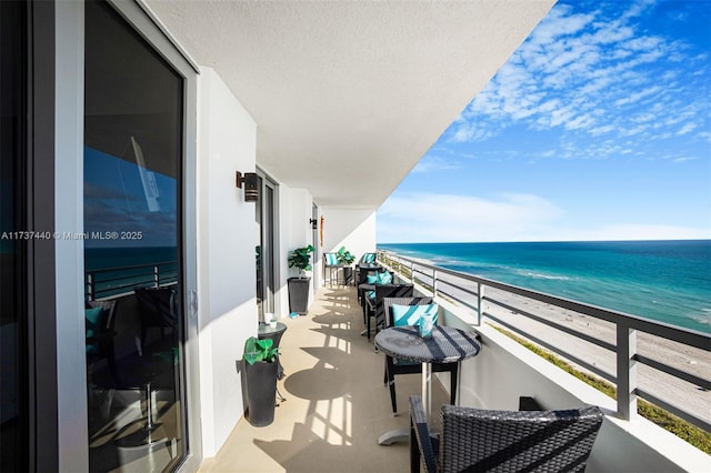 balcony with a water view and a view of the beach