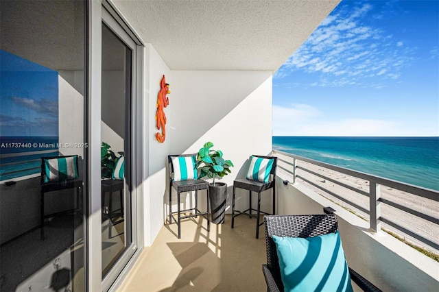 balcony featuring a water view and a beach view