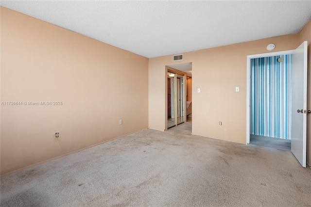 spare room with light carpet and a textured ceiling