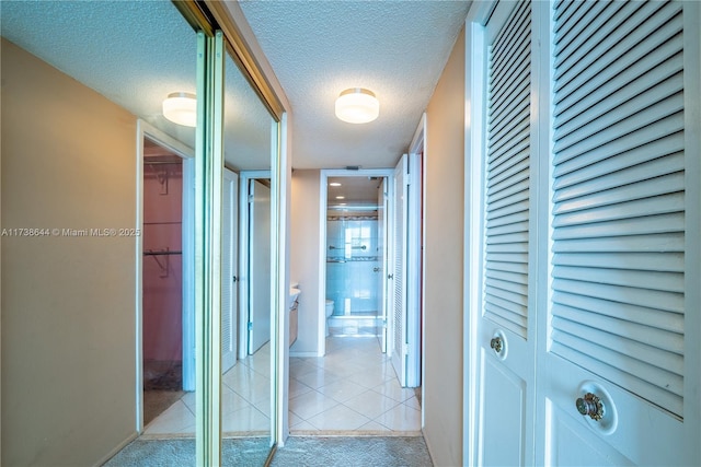 hallway featuring light colored carpet and a textured ceiling