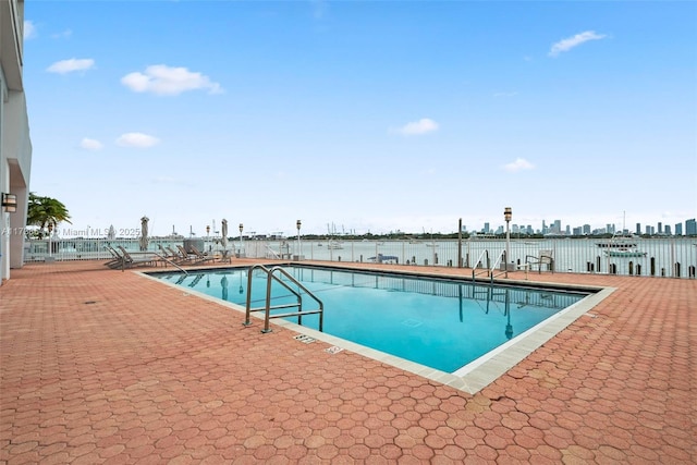 view of swimming pool featuring a water view and a patio area