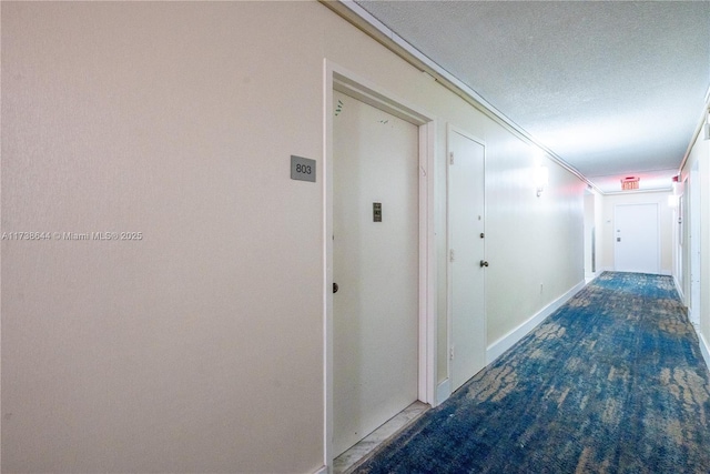 hallway featuring dark colored carpet and a textured ceiling