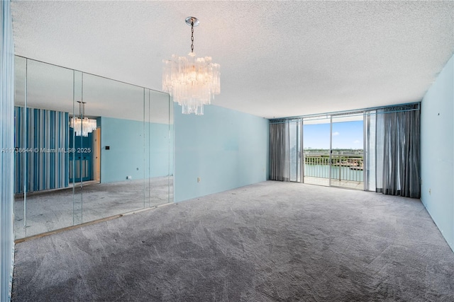 spare room featuring a water view, expansive windows, carpet floors, and a notable chandelier