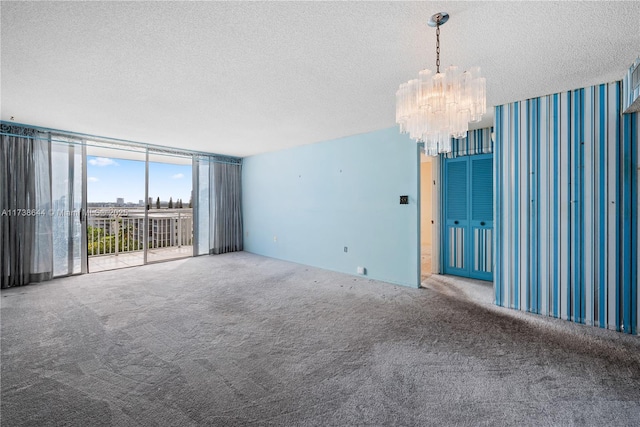 carpeted spare room featuring a notable chandelier, floor to ceiling windows, and a textured ceiling