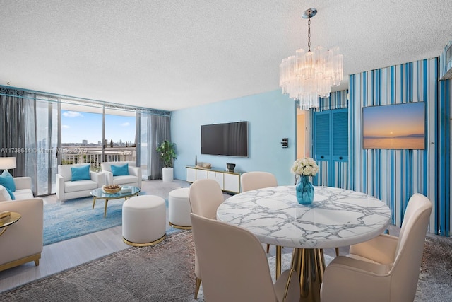 dining space featuring hardwood / wood-style flooring, a chandelier, a textured ceiling, and a wall of windows