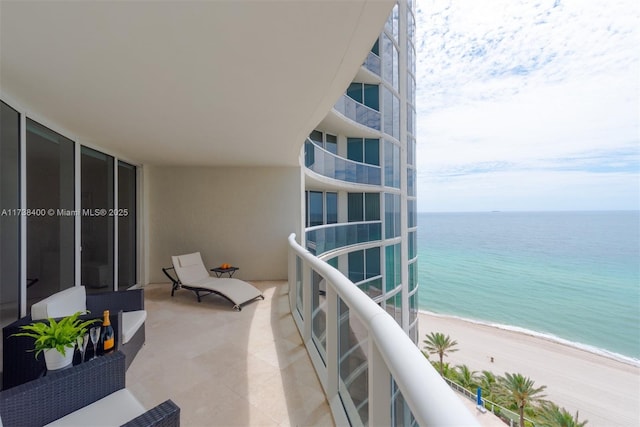 balcony with a water view and a view of the beach