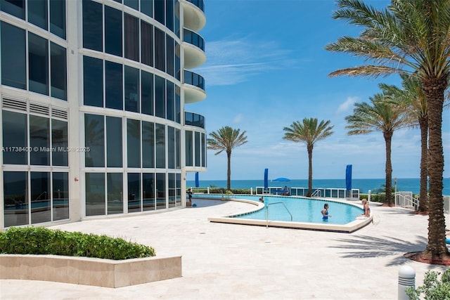 view of swimming pool with a water view and a patio