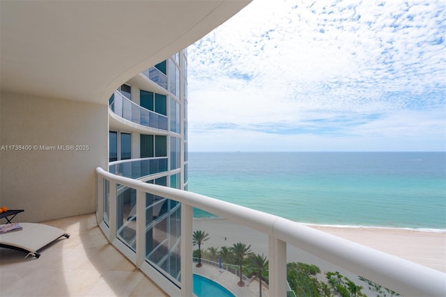 balcony with a water view and a view of the beach